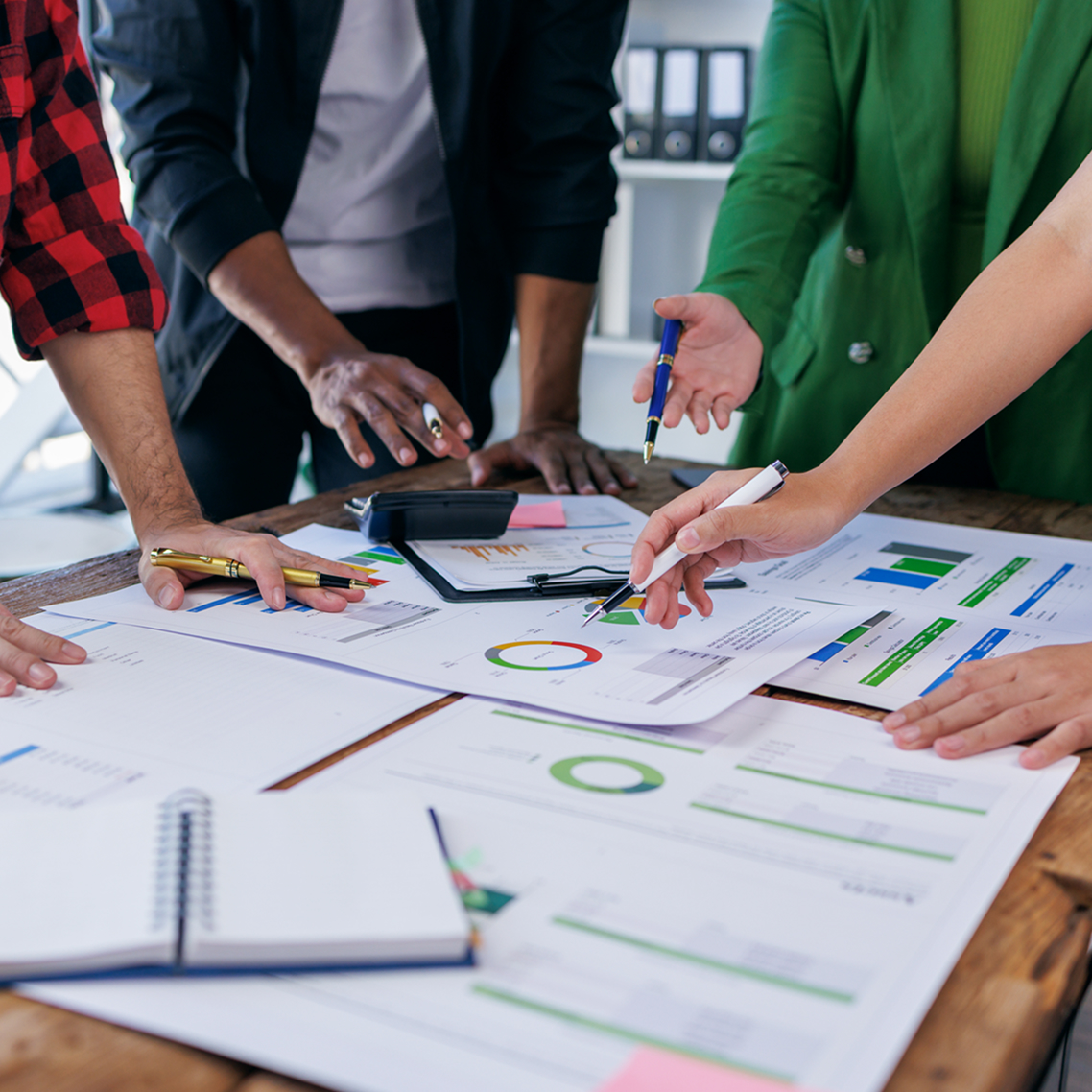 people around a table with printed out graphs and data